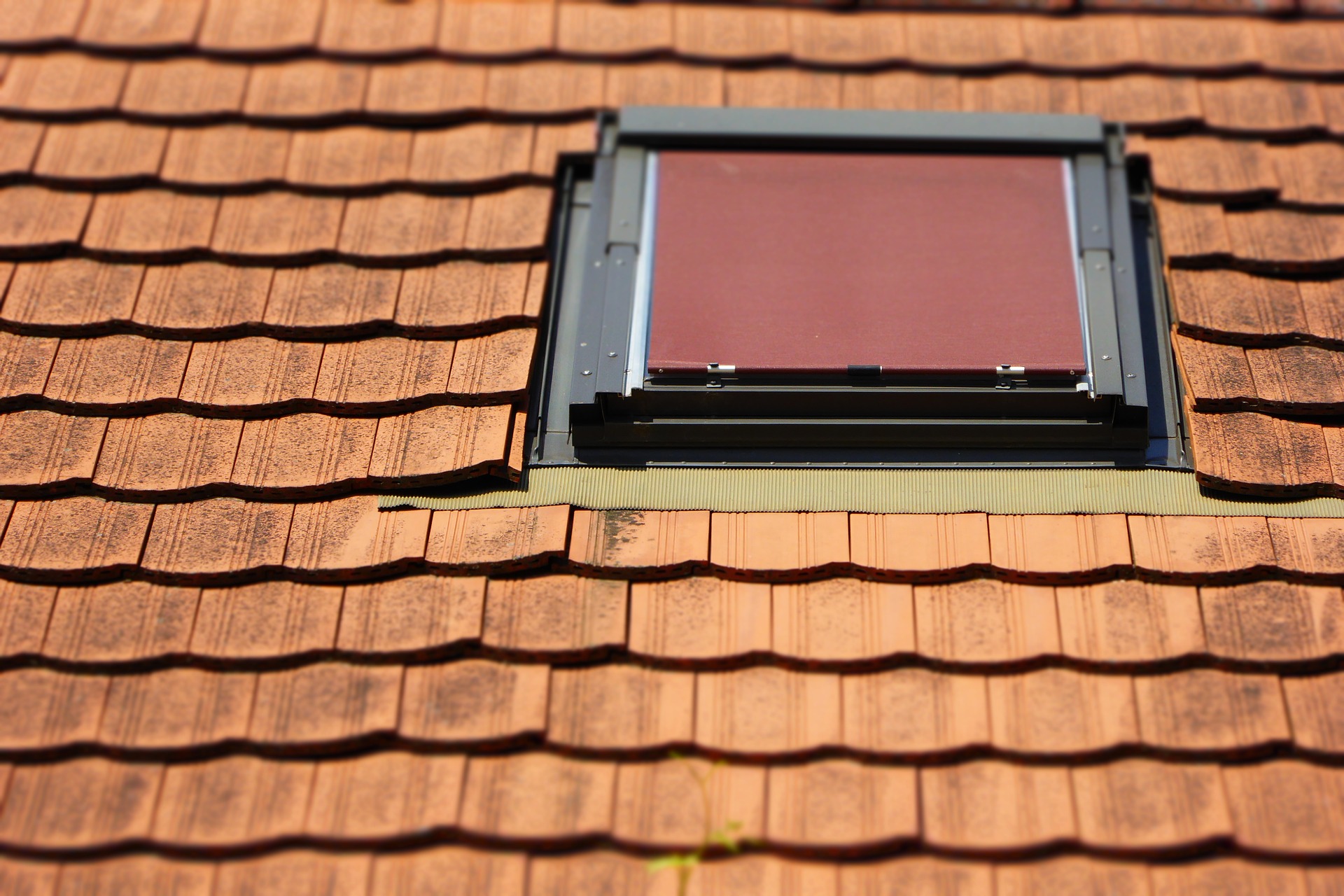 Ein Dachfenster auf einem Dach an einem sonnigem Tag.